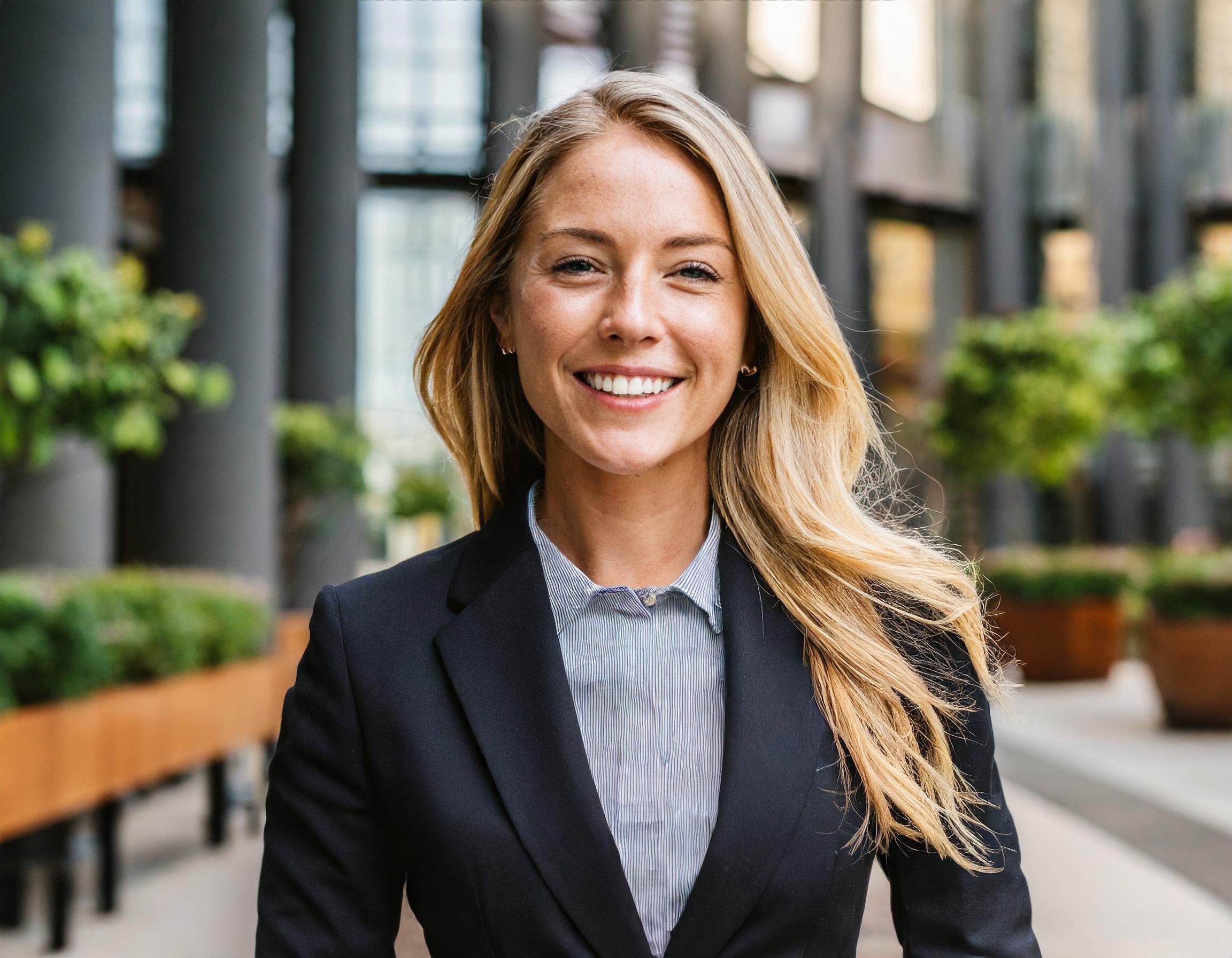 Bild einer lächelnden Frau in Geschäftskleidung, entspannt und freundlich