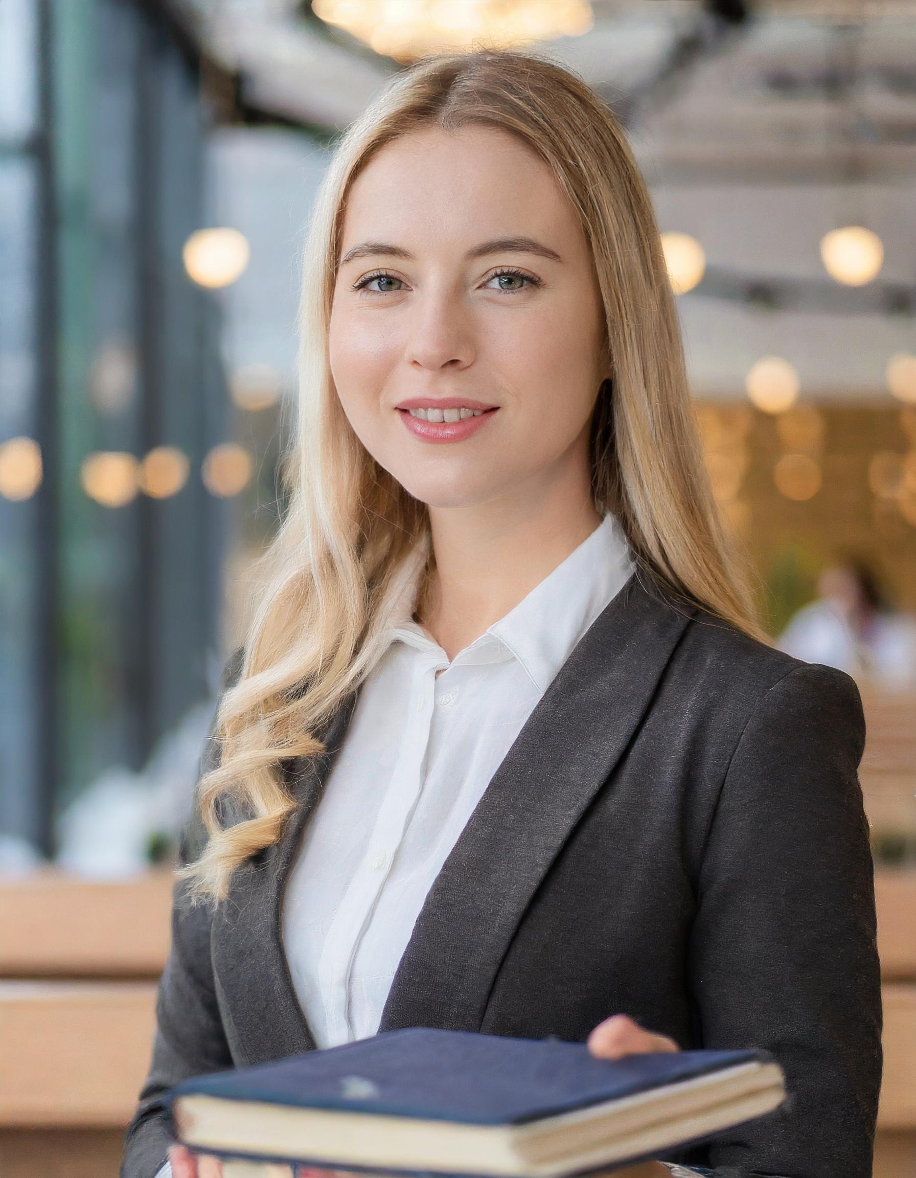 Portrait einer professionell gekleideten Frau, lächelnd, im Büro